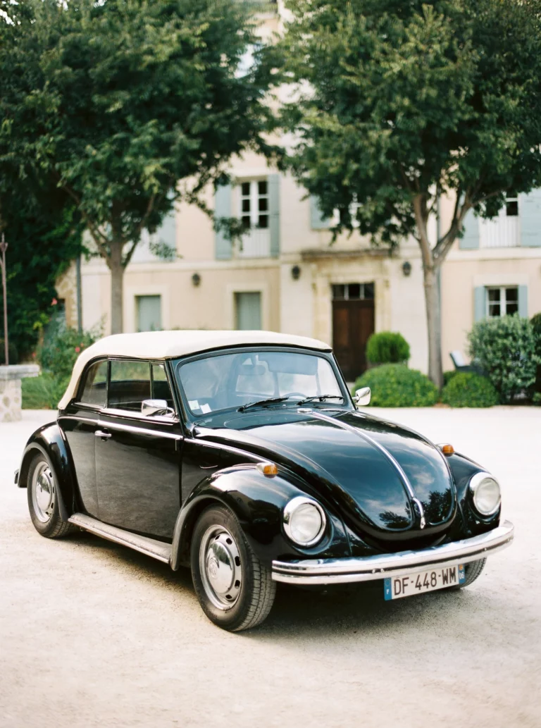 Coccinelle Volkswagen vintage noire devant un château français, photo de couple.