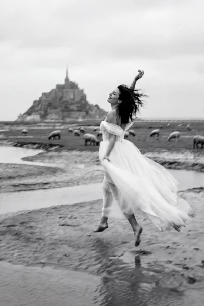 Bride jumping on the beach with Mont Saint-Michel background by a French wedding photographer.