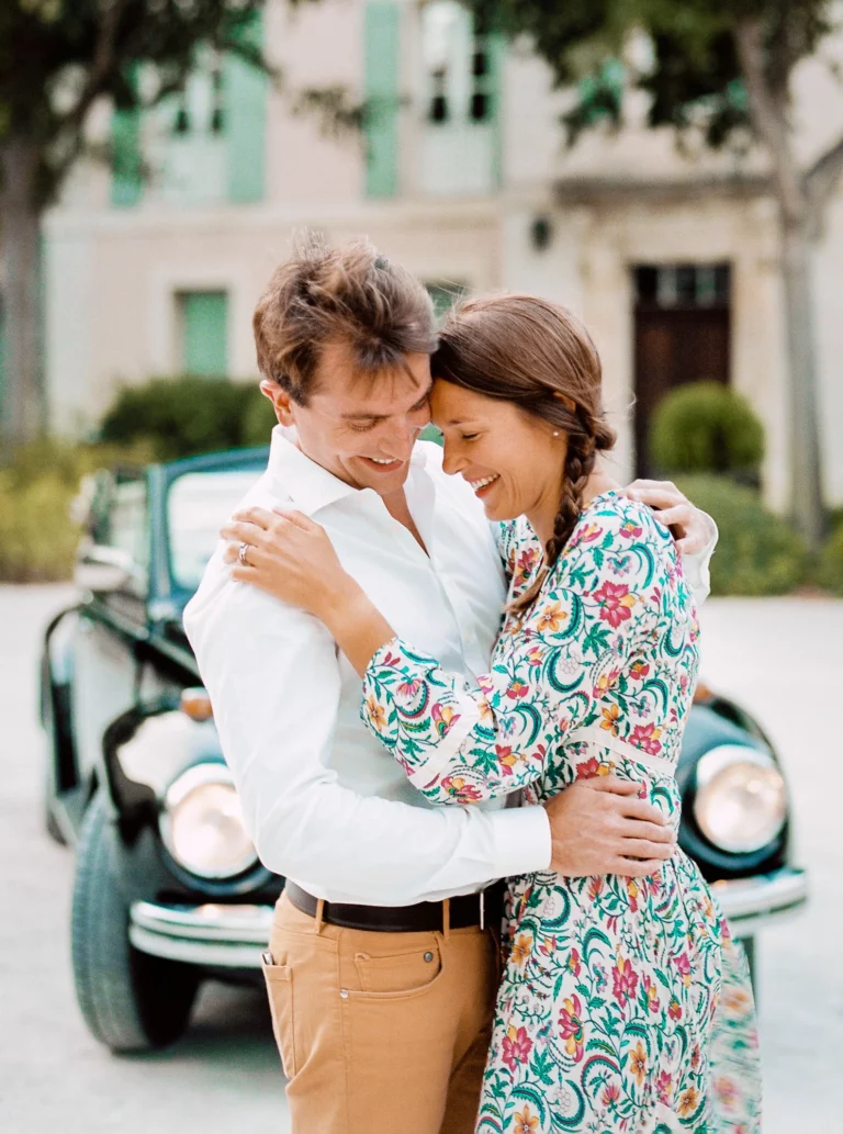 Couple joyeux s'enlaçant près d'une voiture ancienne, capturé par un photographe de mariage photo de couple.