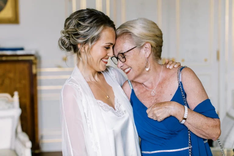 Emotional bride and mother share a laugh during preparations with a French wedding photographer.