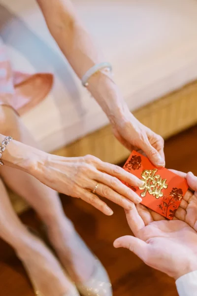 Traditional red envelope exchange captured by a French wedding photographer during a luxury cultural ceremony.