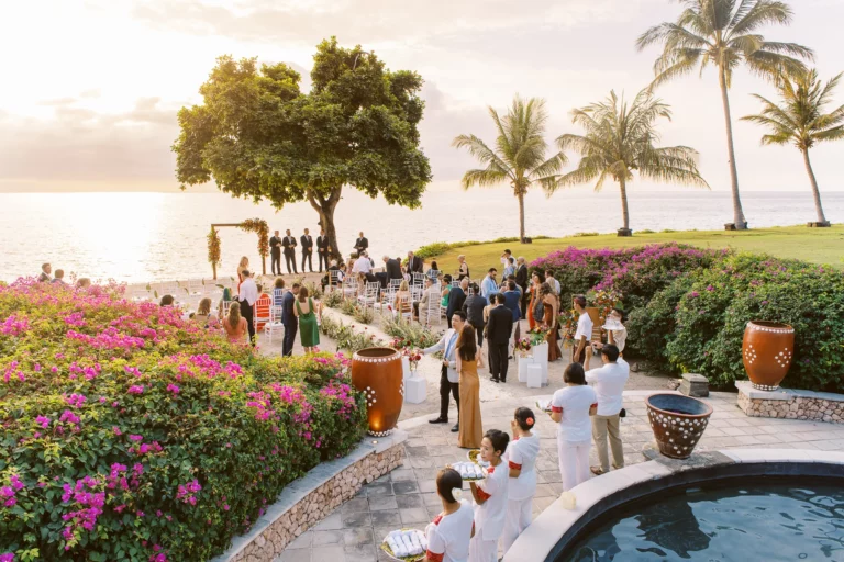 Guests mingling at a luxury seaside ceremony captured by a French wedding photographer during golden hour.