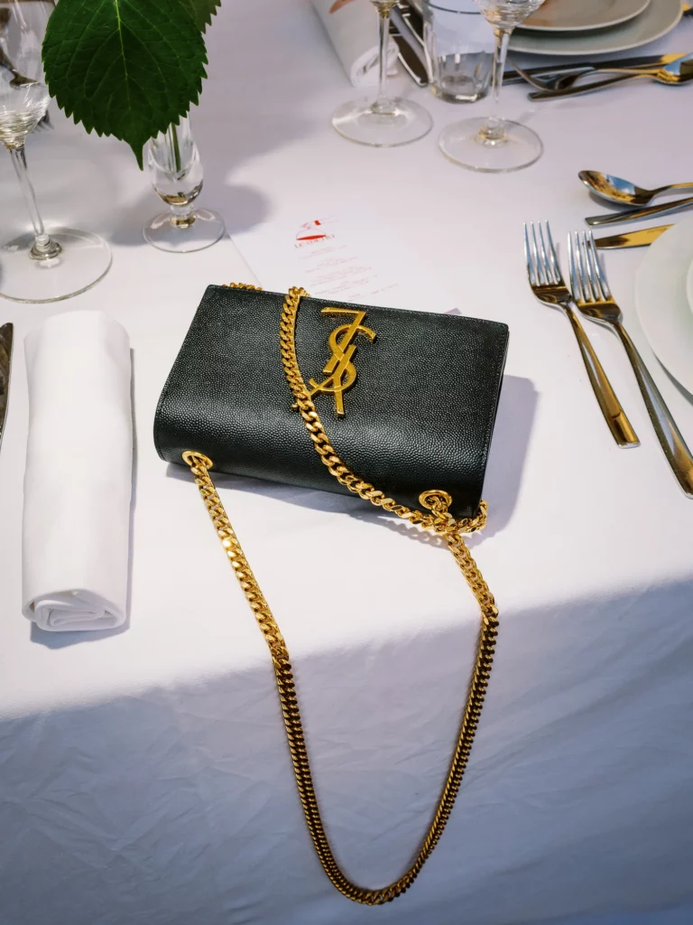 Black YSL bag on a luxury table captured by a French wedding photographer wedding photographer.