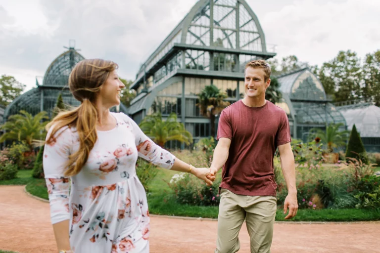 Couple se tenant la main devant une serre avec un photographe de couple.