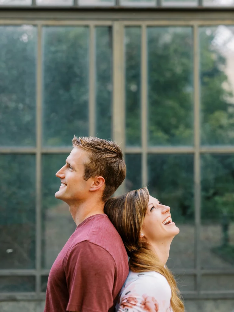 Couple complice riant dos à dos lors d'une séance avec un photographe de mariage pour photos à deux.