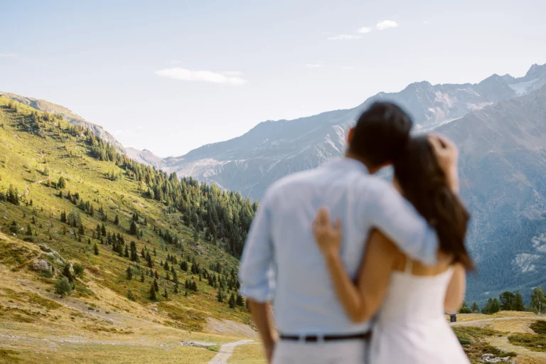 Couple s'enlaçant devant les montagnes ensoleillées, photographe de mariage pour couple.