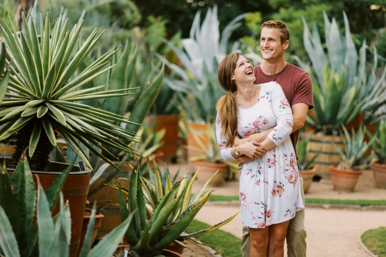 Un couple joyeux riant dans un jardin botanique luxuriant par un photographe de mariage photo de couple.