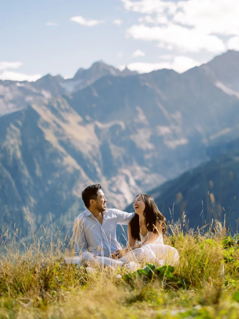 Couple riant aux éclats dans une prairie alpine, photographe de mariage elopement en montagne.
