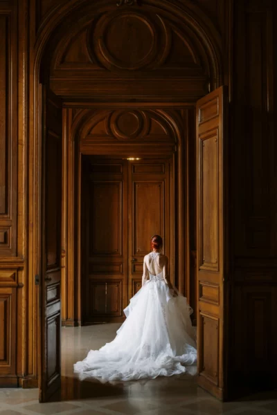 Bride in a white gown by ornate doors with French wedding photographer.