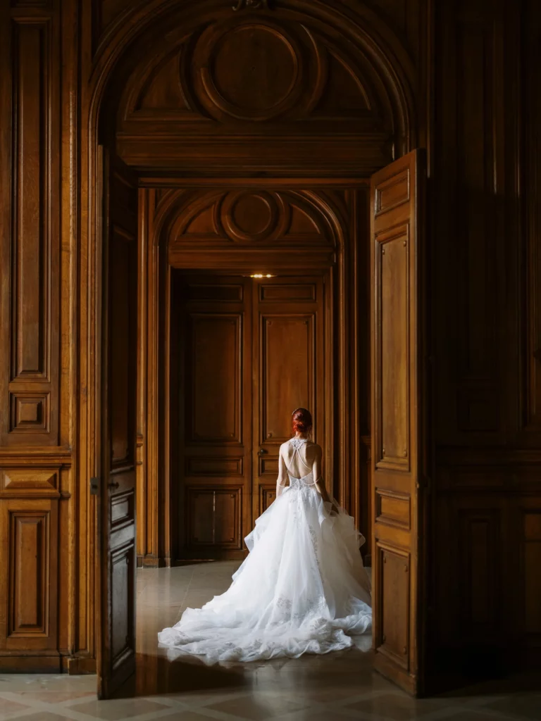 Bride in a white gown by ornate doors with French wedding photographer wedding photographer.