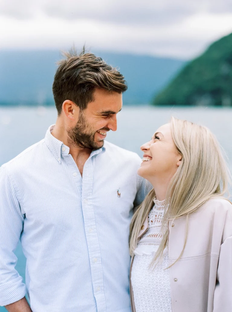 Un couple complice riant au bord de l'eau, immortalisé par un photographe de mariage.
