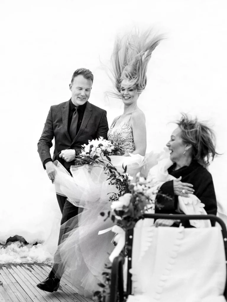 A joyful bride with wind-blown hair at a snow-covered venue by a French wedding photographer.
