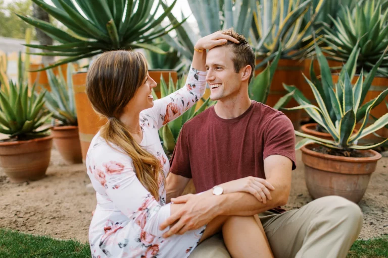 Un couple joyeux assis dans un jardin d'agaves capturé par un photographe de mariage photo de couple.