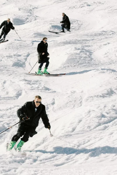 Groomsmen skiing in fur coats captured by a french wedding photographer in the Alps.