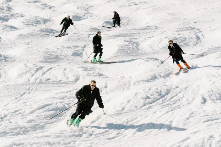 Groomsmen skiing in fur coats captured by a french wedding photographer wedding photographer in the Alps.