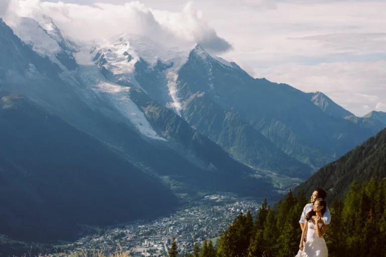 Couple s'enlaçant sur une crête de montagne surplombant la vallée par un photographe de mariage de couple.