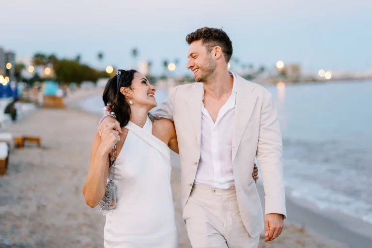 Couple riant sur la plage au coucher du soleil par un photographe de couple.