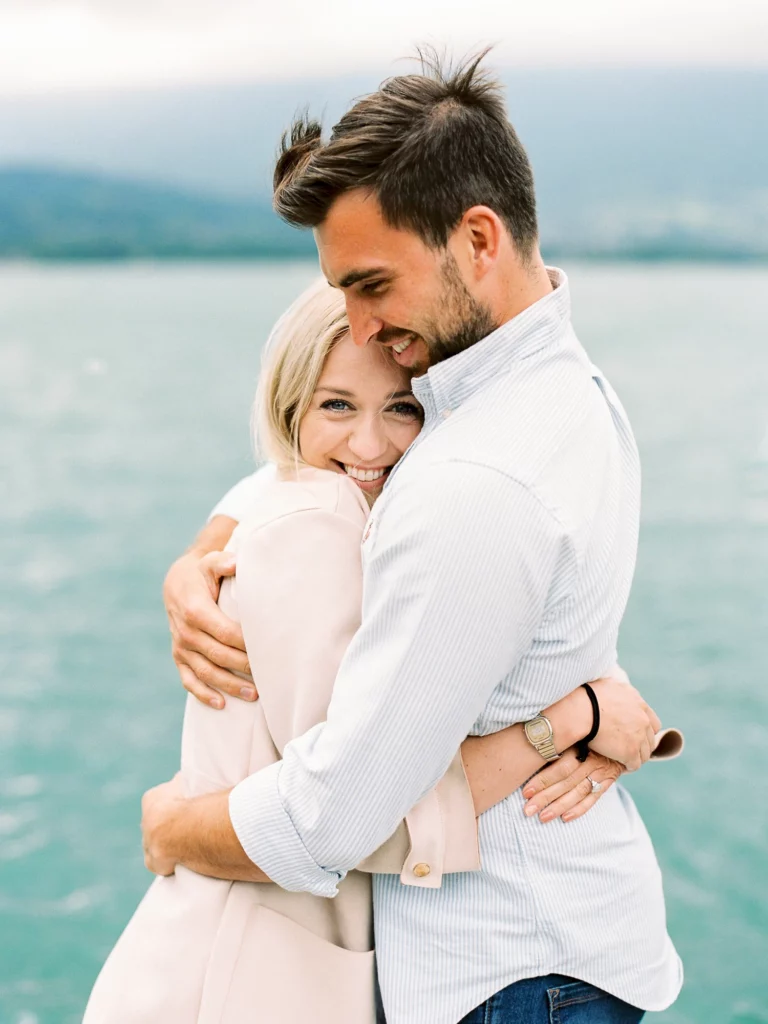Un couple radieux s'enlace au bord de l'eau, immortalisé par un photographe de mariage.