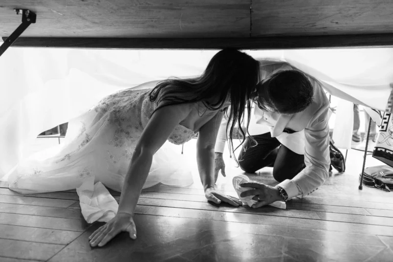 Bride and groom hiding under a table, captured by a french wedding photographer wedding photographer.