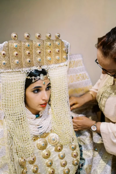 A Moroccan bride in traditional gold regalia during preparation by a French wedding photographer.