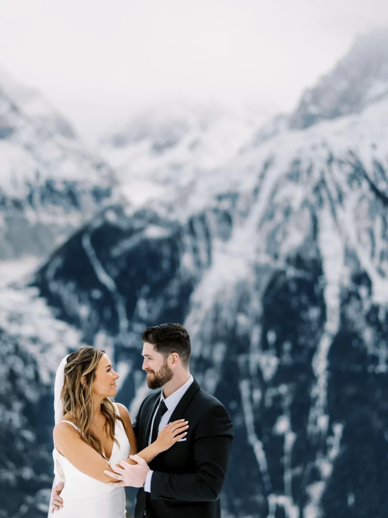 Mariés s'enlaçant devant les sommets enneigés capturés par un photographe de mariage lors d'un elopement.