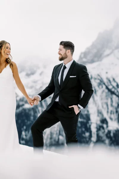 Bride and groom holding hands in snowy mountains captured by a French wedding photographer.