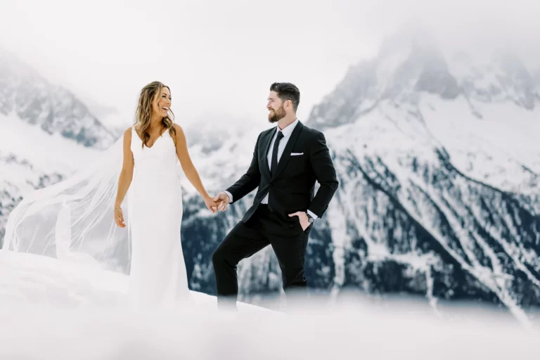 Bride and groom holding hands in snowy mountains captured by a French wedding photographer.