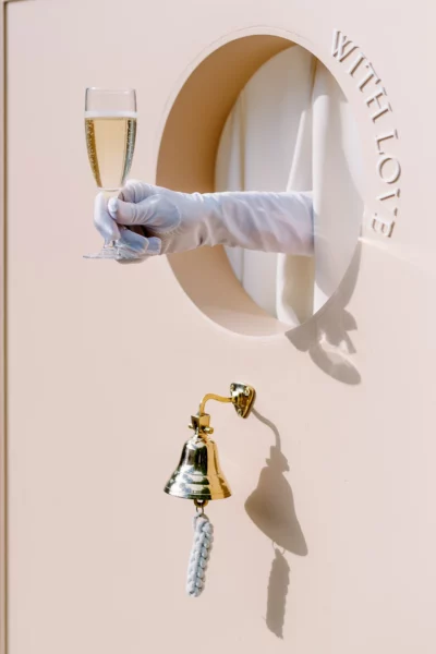 A gloved hand serving a glass of champagne from a luxury wall, captured by a French wedding photographer.