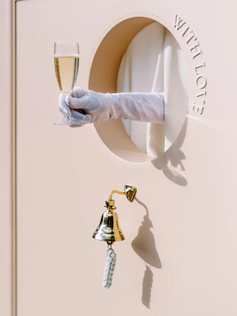 A gloved hand serving a glass of champagne from a luxury wall, captured by a French wedding photographer.