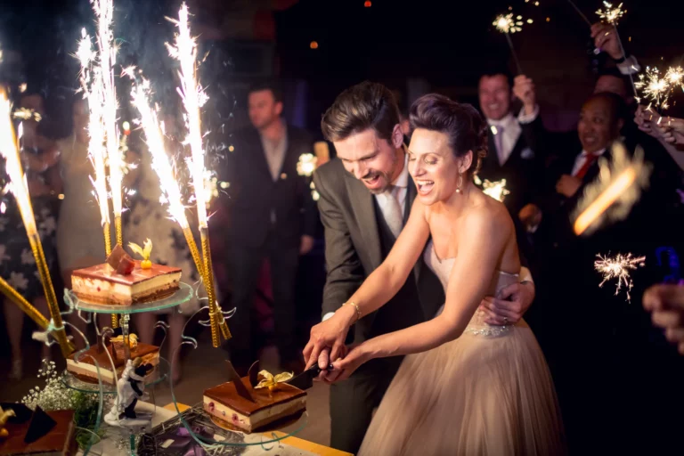 Joyful bride and groom cutting cake with sparklers by a French wedding photographer.