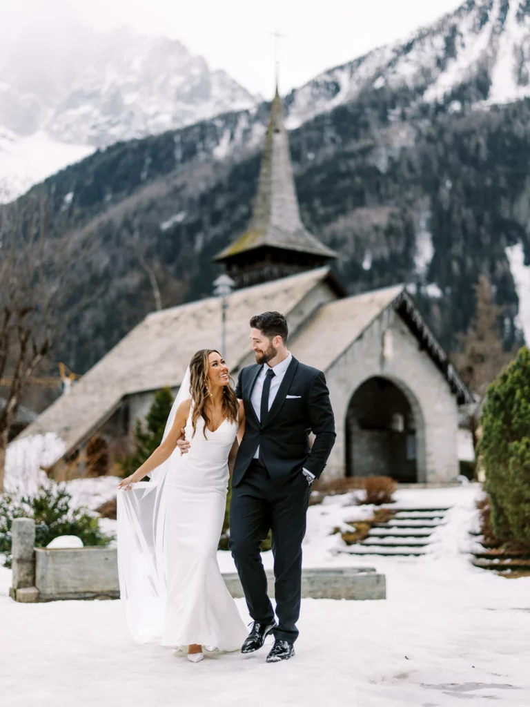Mariés marchant dans la neige à la Chapelle des Praz avec un photographe de mariage.