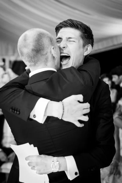Emotional groom embrace during reception speeches captured by a french wedding photographer.