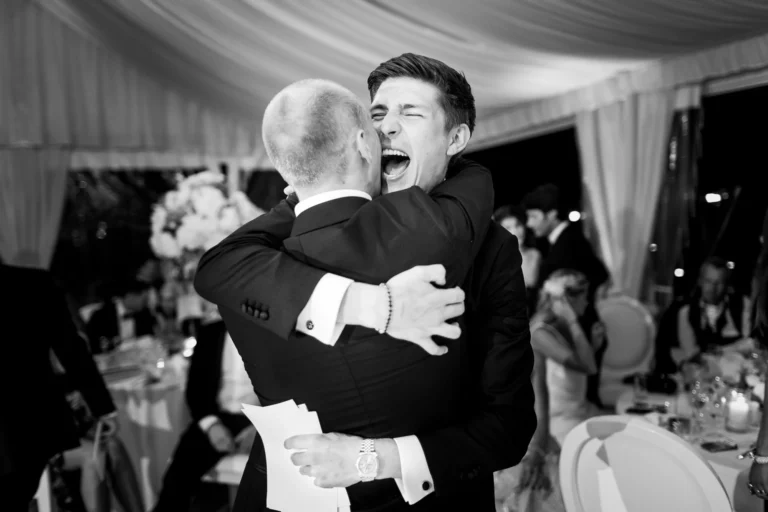 Emotional groom embrace during reception speeches captured by a french wedding photographer wedding photographer.