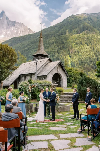 French wedding photographer capturing an outdoor ceremony at a stone chapel in the Alps.