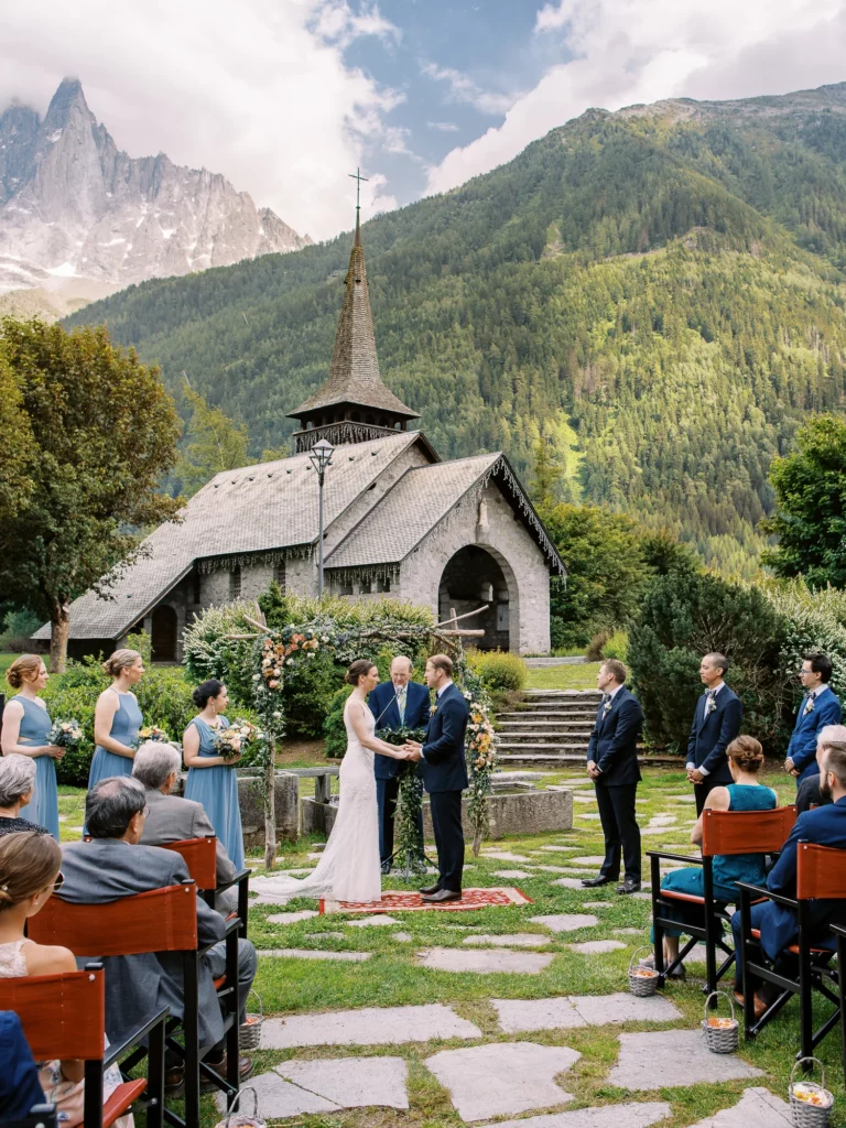 French wedding photographer capturing an outdoor ceremony at a stone chapel in the Alps.