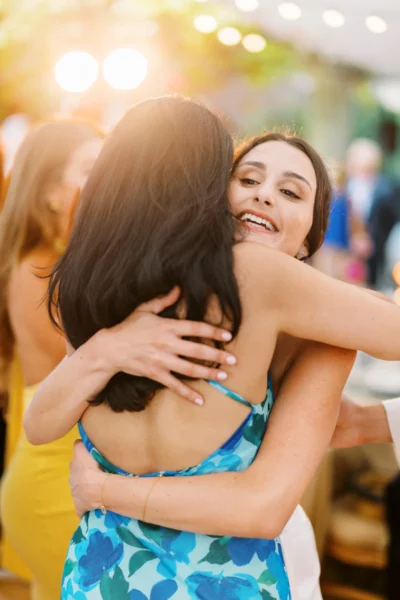 Joyful guests embrace during a golden hour reception by a French wedding photographer.