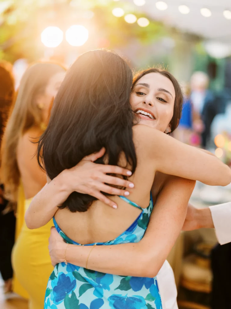 Joyful guests embrace during a golden hour reception by a French wedding photographer.