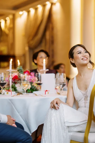 Bride smiling at her luxury reception dinner captured by a French wedding photographer in a ballroom.
