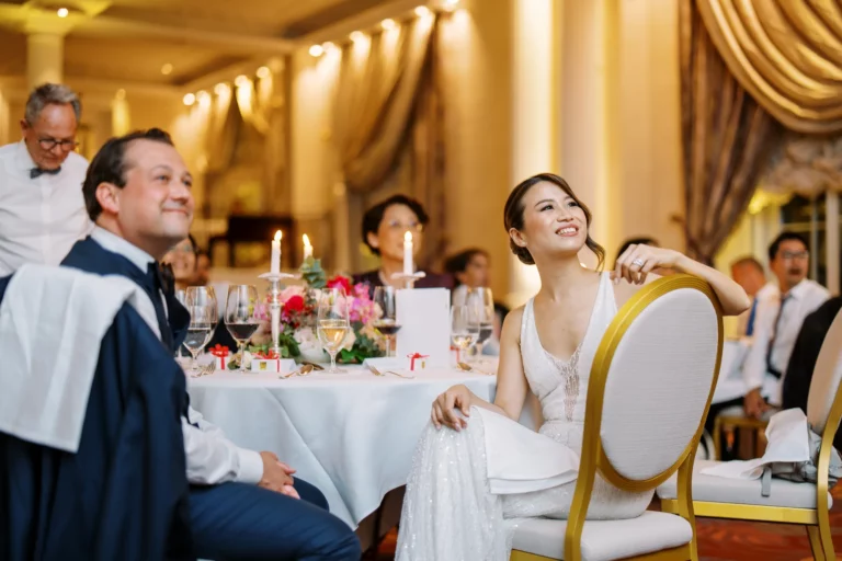 Bride smiling at her luxury reception dinner captured by a French wedding photographer in a ballroom.