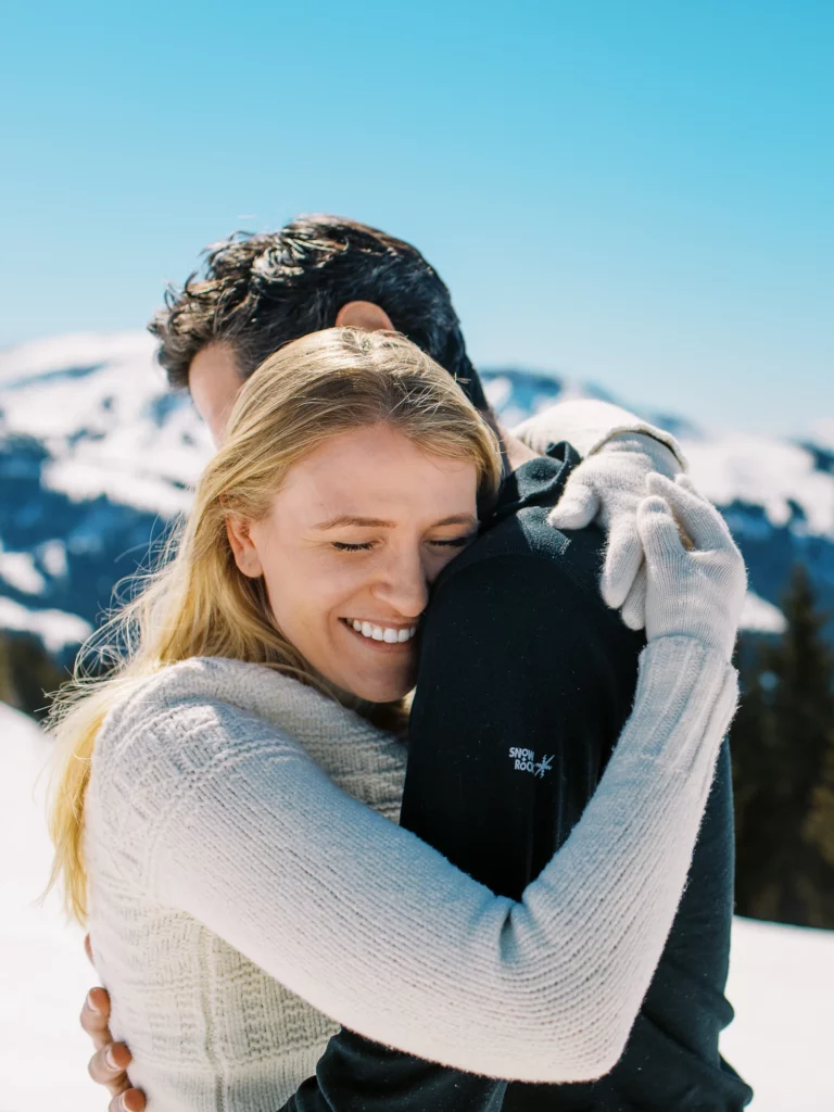Femme blonde souriante serrant son partenaire dans les montagnes par un photographe de photo de couple.
