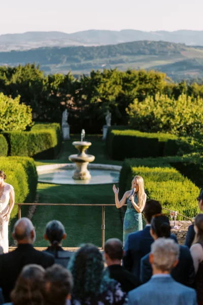 Outdoor wedding speech in a manicured garden captured by a French wedding photographer.