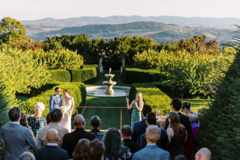 Outdoor wedding speech in a manicured garden captured by a French wedding photographer.