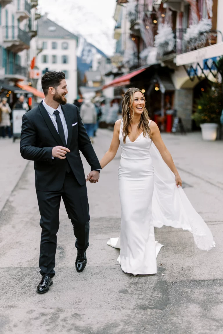 Mariés marchant dans les rues d'un village alpin capturés par un photographe de mariage.