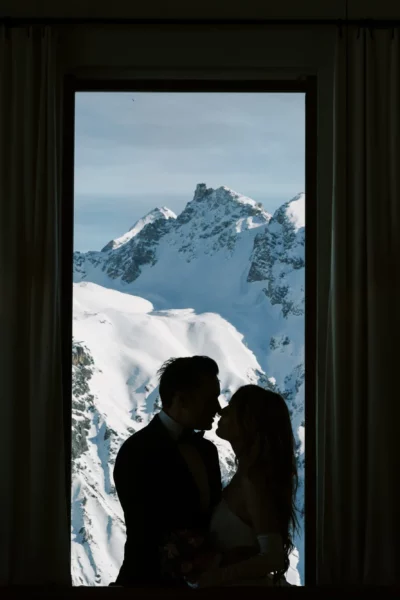 Silhouette of a couple against snowy peaks captured by a French wedding photographer in the Alps.