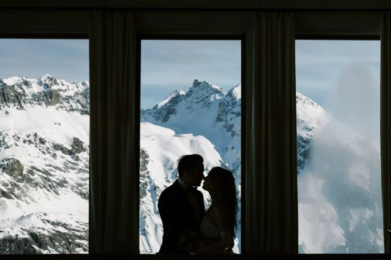 Silhouette of a couple against snowy peaks captured by a French wedding photographer in the Alps.