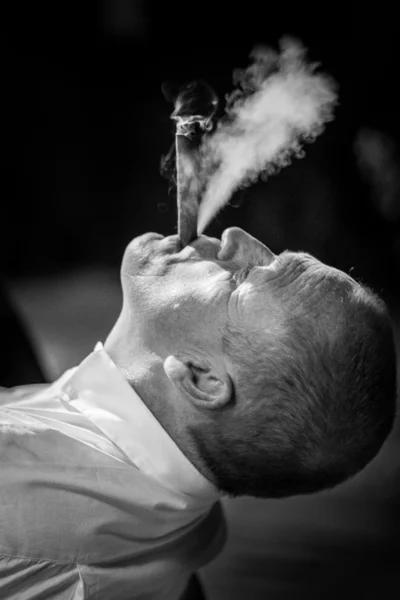 A man smoking a cigar in black and white by a French wedding photographer.