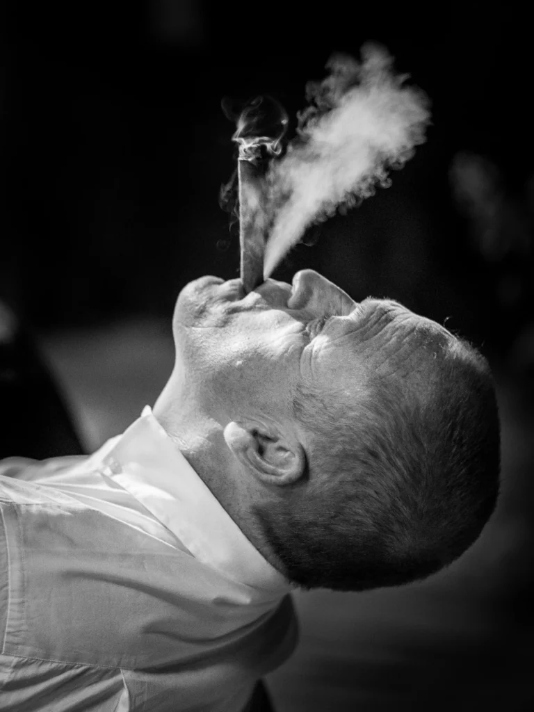 A man smoking a cigar in black and white by a French wedding photographer.