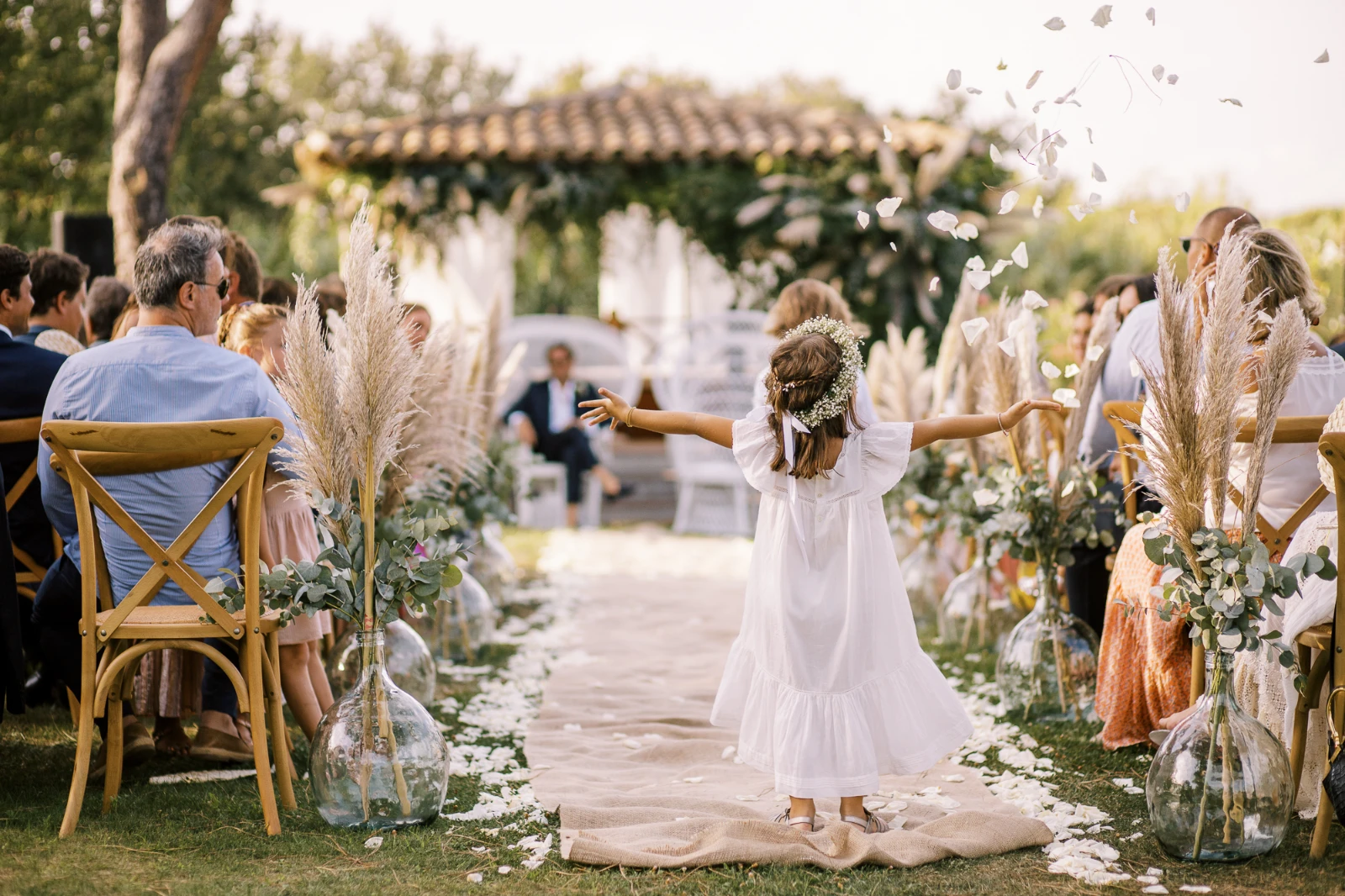 Flower girl tossing white petals during a garden wedding ceremony on the French Riviera in Cannes.