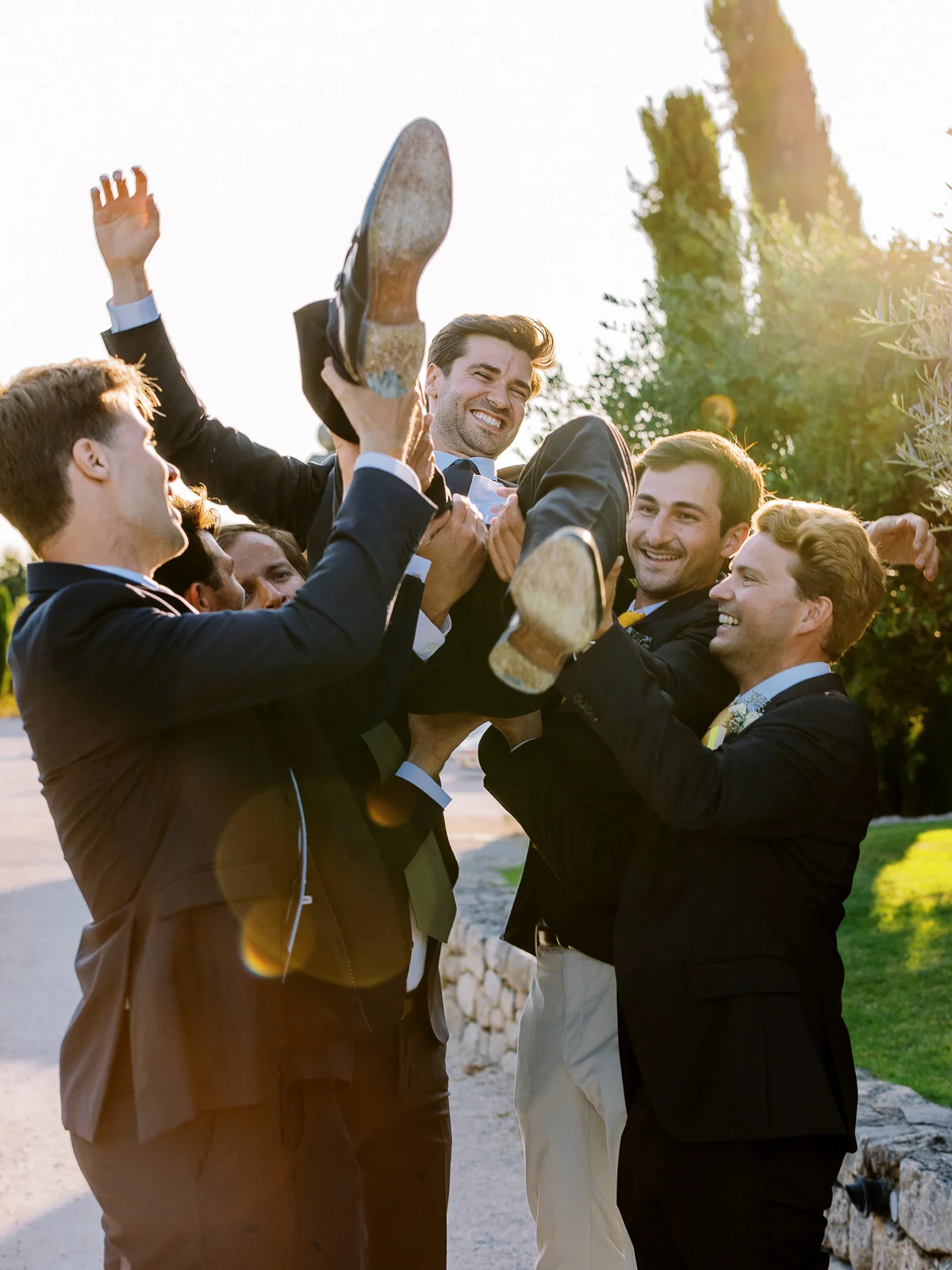 Garçons d'honneur soulevant le marié lors d'une célébration capturée par un photographe mariage france.