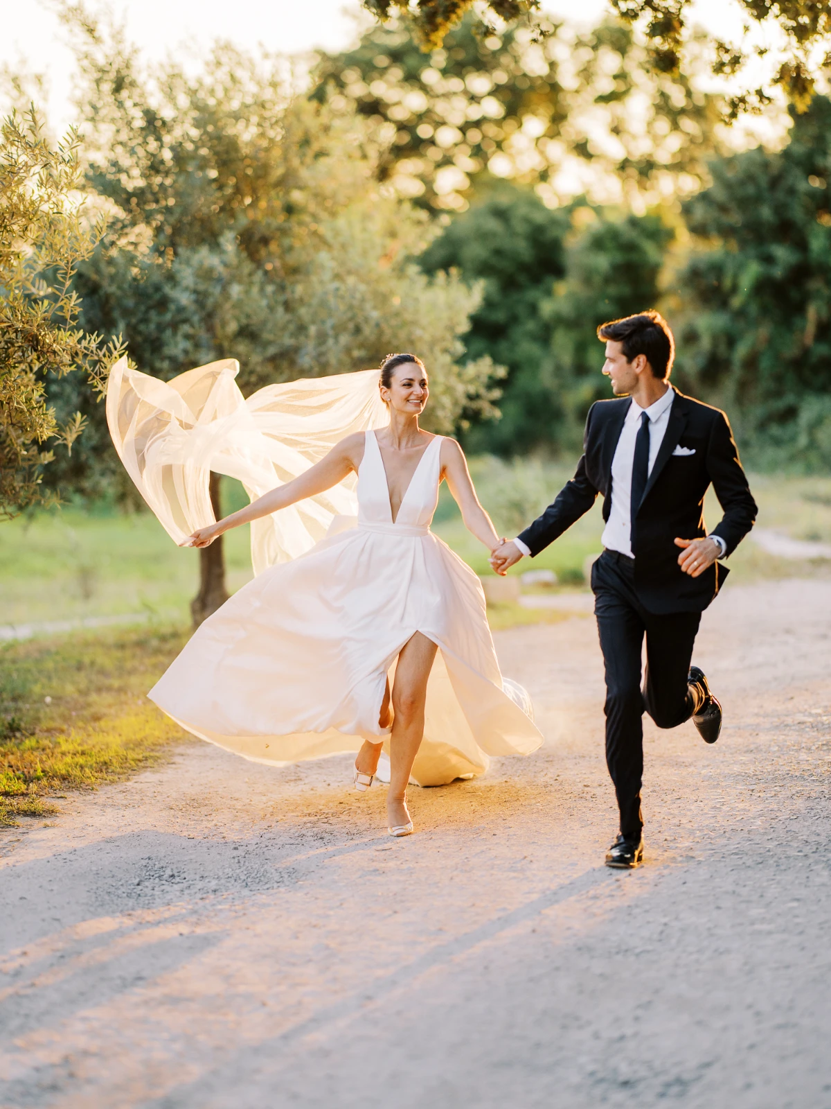 A joyful couple running through a lush French Riviera estate during the golden hour.